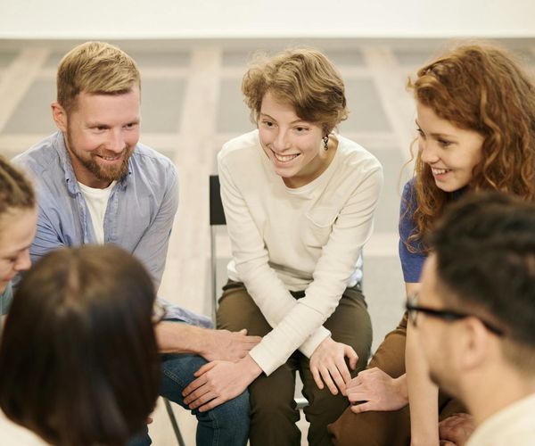 Group of diverse people sitting in a circle on yoga mats in a bright room.